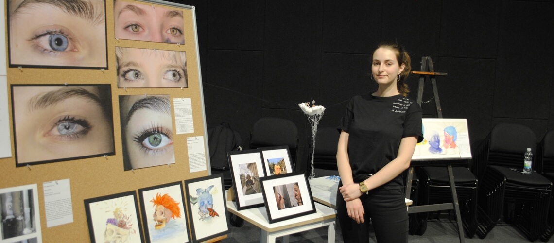 Student showing of her paintings and photos